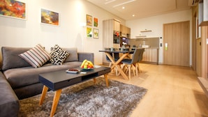A modern living room with a grey sofa, a black coffee table, and a dining area with a wooden table and chairs.