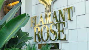 A hotel sign with the name "FLAMANT ROSE" in gold letters on a white wall.