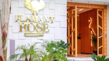 La entrada a 'Flamant Rose Apartments', con un llamativo logo de cisne y una puerta de madera.