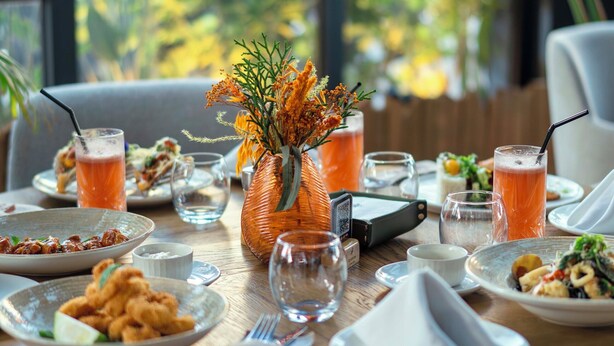 A dining table set with plates, glasses, and a vase of flowers.