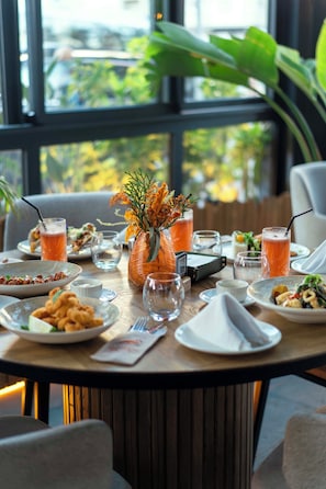 A dining table set with plates, glasses, and a vase of flowers. - Flamant Rose Appart Hôtel (Tangier)