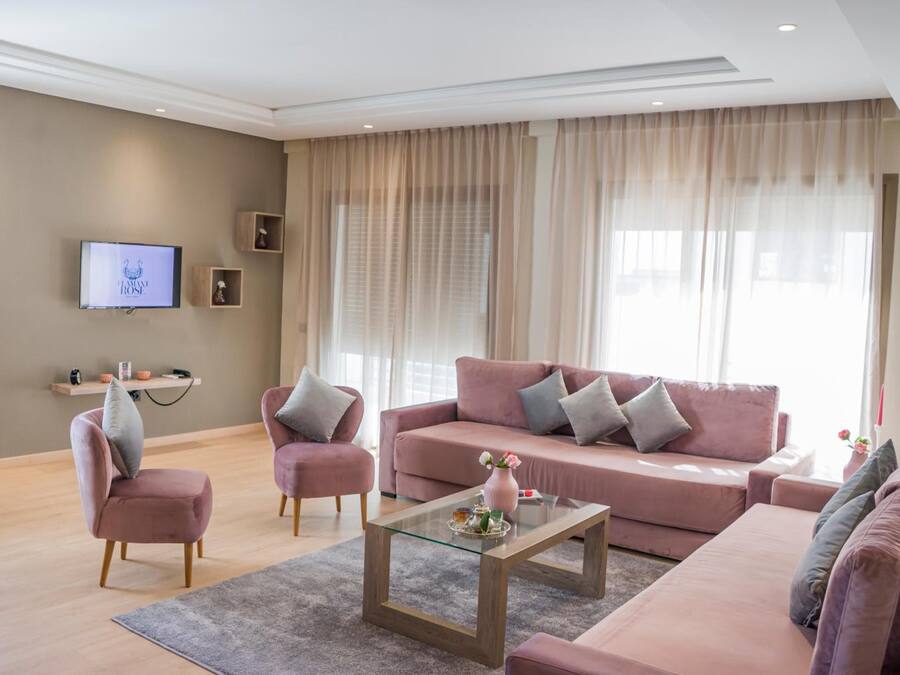 Ein modernes Wohnzimmer mit einem rosa Sofa, einem Glastisch und einem flachbildfernseher an der Wand.
