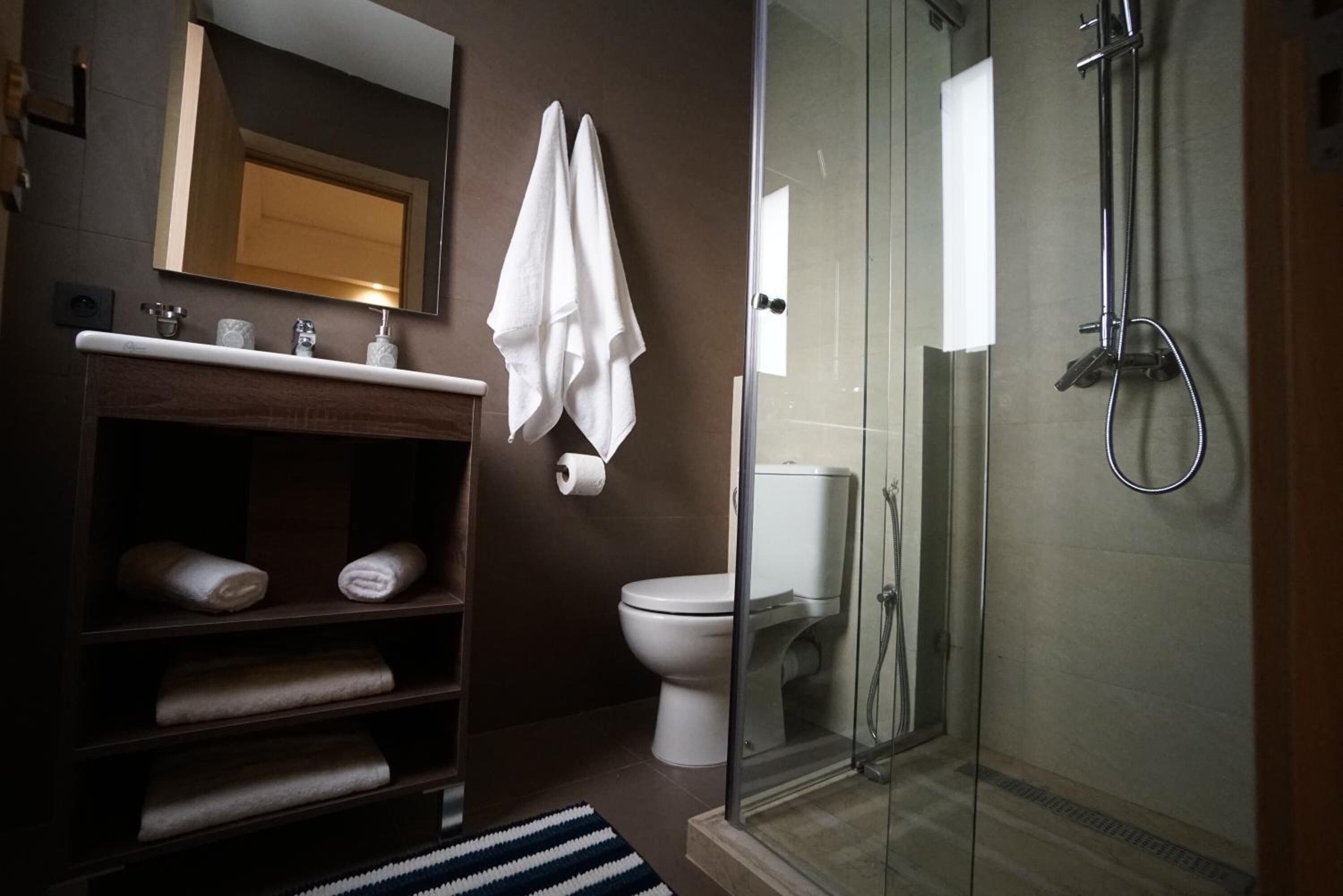 Un bagno moderno con doccia vetrata, un water e un mobile lavabo con asciugamani.