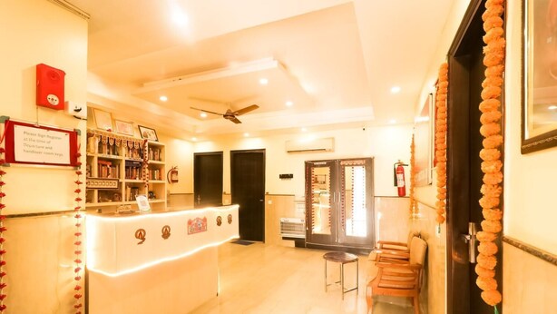A hotel reception area with a counter, bookshelves, a fire extinguisher, and a sign instructing to sign register at the time of departure. - GD House (Gurugram)