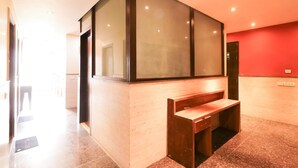 A modern interior with a wooden bench, a glass partition, and a red wall. - GD House (Gurugram)