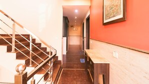A staircase leading to a room with a red wall and a framed picture. - GD House (Gurugram)