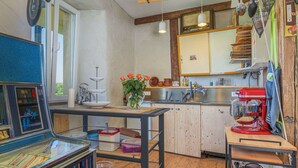 A kitchen with wooden cabinets, a sink, and a red mixer. There is a window with a view of greenery outside.