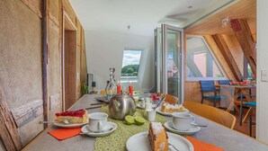 A dining area with a table set for two, featuring a cake and a teapot.