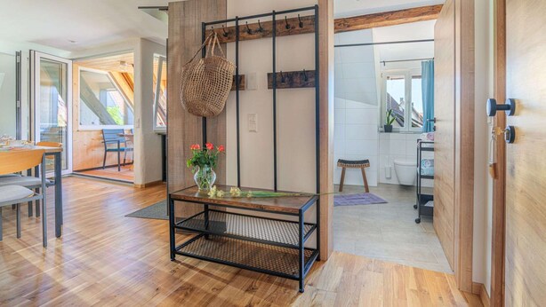 A modern interior with a wooden floor, a glass table with a woven basket, and a view of the outside.