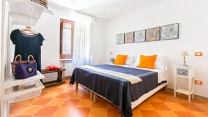 Une chambre à coucher comprenant un lit, une commode, un portant à vêtements, une fenêtre et un mur décoré d’œuvres d’art.