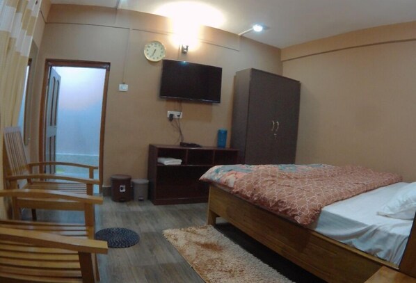 Un dormitorio con cama, televisor, armario y silla.