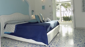 Ein Schlafzimmer mit einem Bett, einem Nachttisch und einem Fenster mit Blick auf Grün.