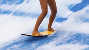 A person standing on a surfboard in a wave pool. - Nori House Kata Beach (Karon)