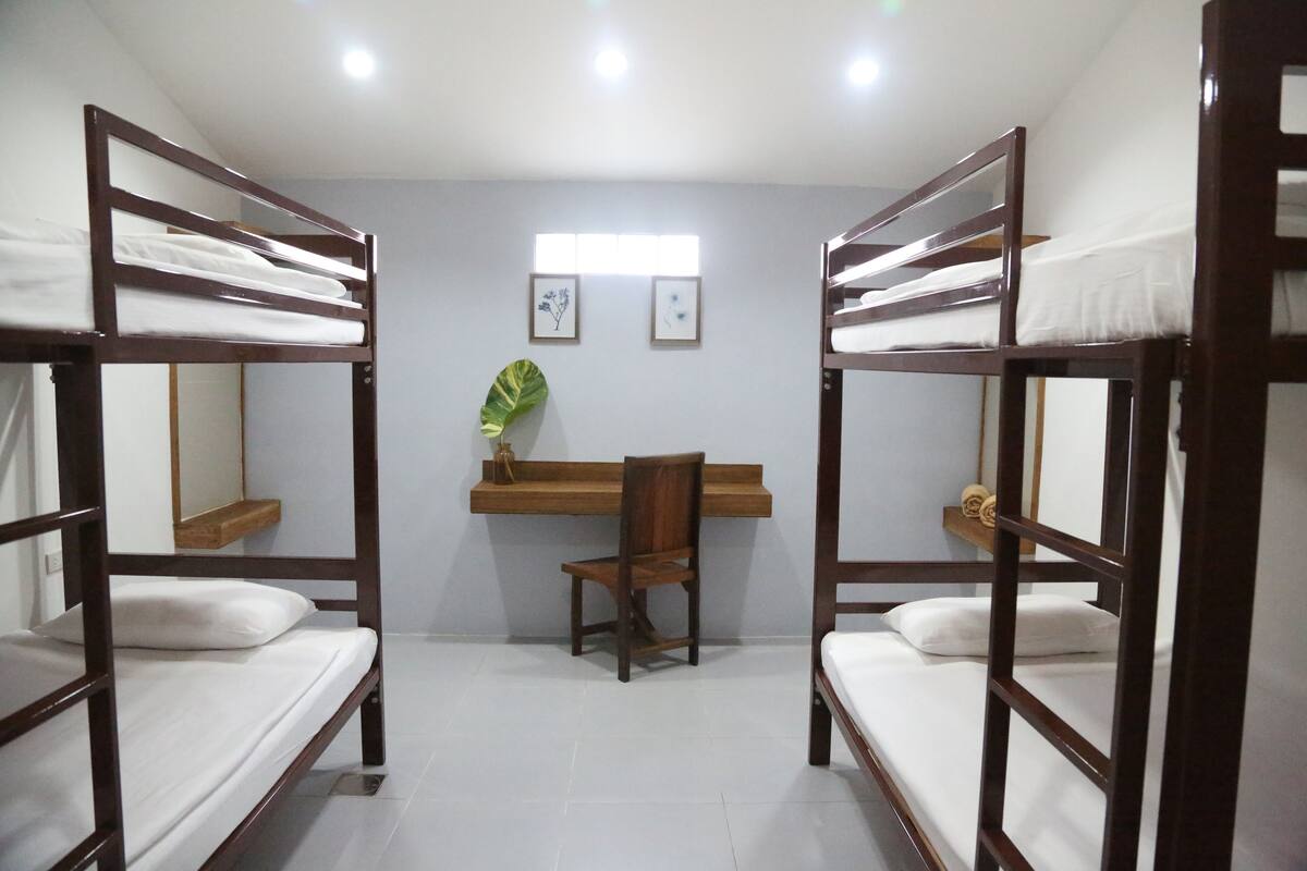A room with bunk beds, a desk, a chair, and a mirror.