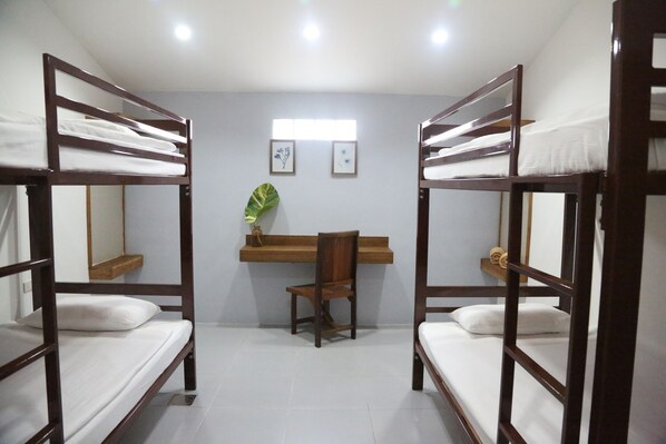 A room with bunk beds, a desk, a chair, and a mirror.