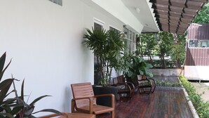 A covered outdoor area with wooden flooring, seating, and potted plants. - Nori House Kata Beach (Karon)