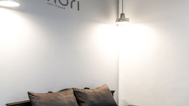 A bedroom with a bed, two wall-mounted lights, and a sign that reads "nori house". - Nori House Kata Beach (Karon)