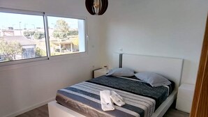 Een slaapkamer met een bed, een raam en uitzicht op buiten.