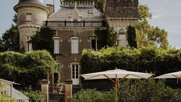 Un bâtiment qui ressemble à un château, avec une piscine et des chaises longues.
