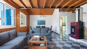 A cozy living room with a checkered floor, wooden ceiling beams, and a modern fireplace.