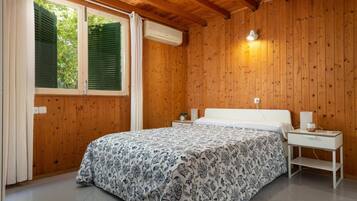 A bedroom with a bed, bedside tables, and a window with shutters.