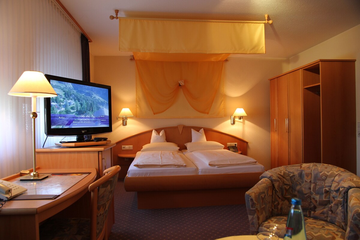 Une chambre d’hôtel comprenant un lit, une télévision, un bureau avec une lampe et une armoire.