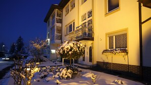 A multi-story building with balconies, snow-covered ground, and a Christmas tree. - Hotel Anika (Neuenburg am Rhein)