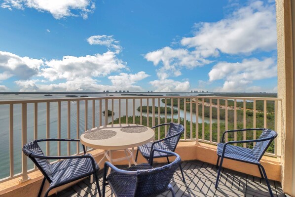 Un balcon avec une table et des chaises donnant sur une rivière et sur le panorama de la ville au loin.
