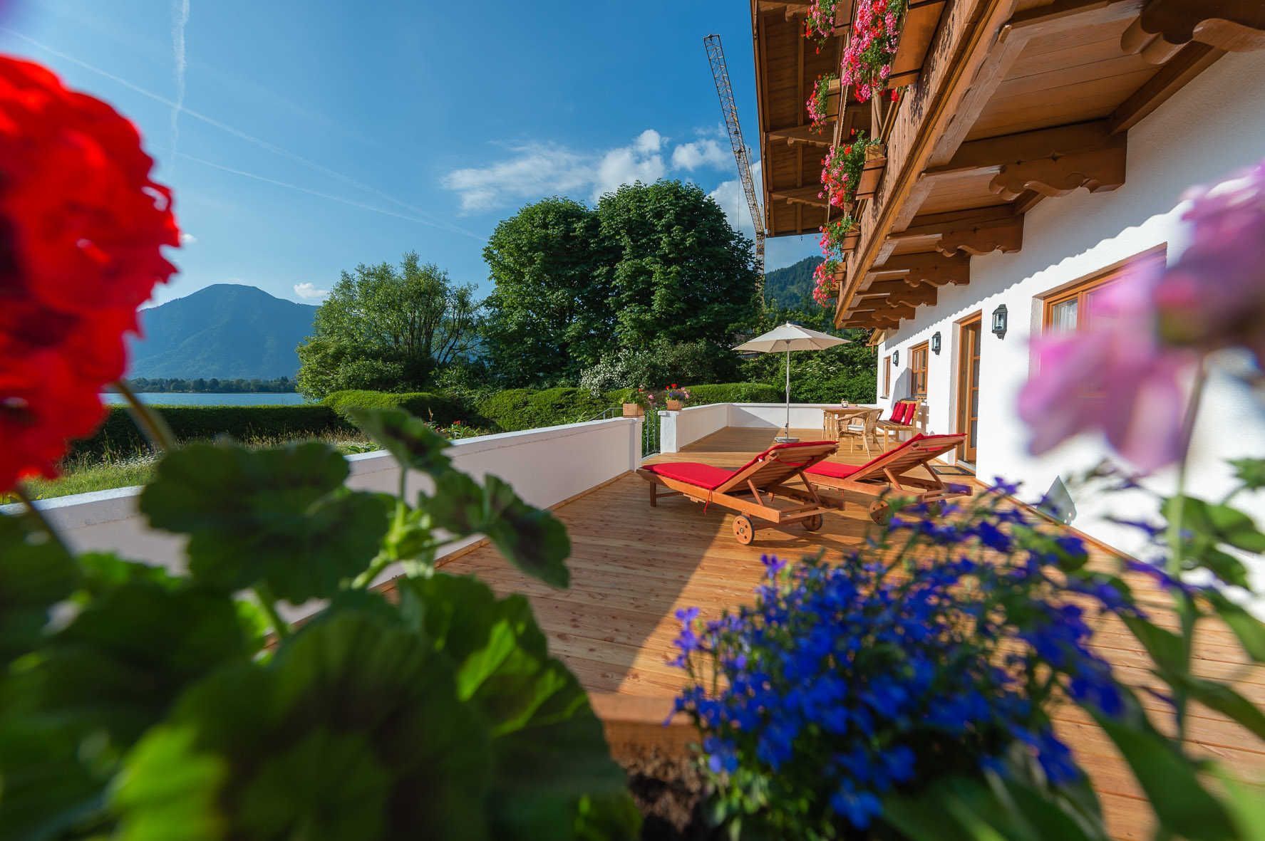 A wooden deck with two lounge chairs, a table, and a hanging flower basket.