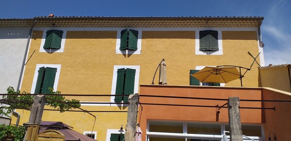 A yellow building with green shutters and a visible garage door.