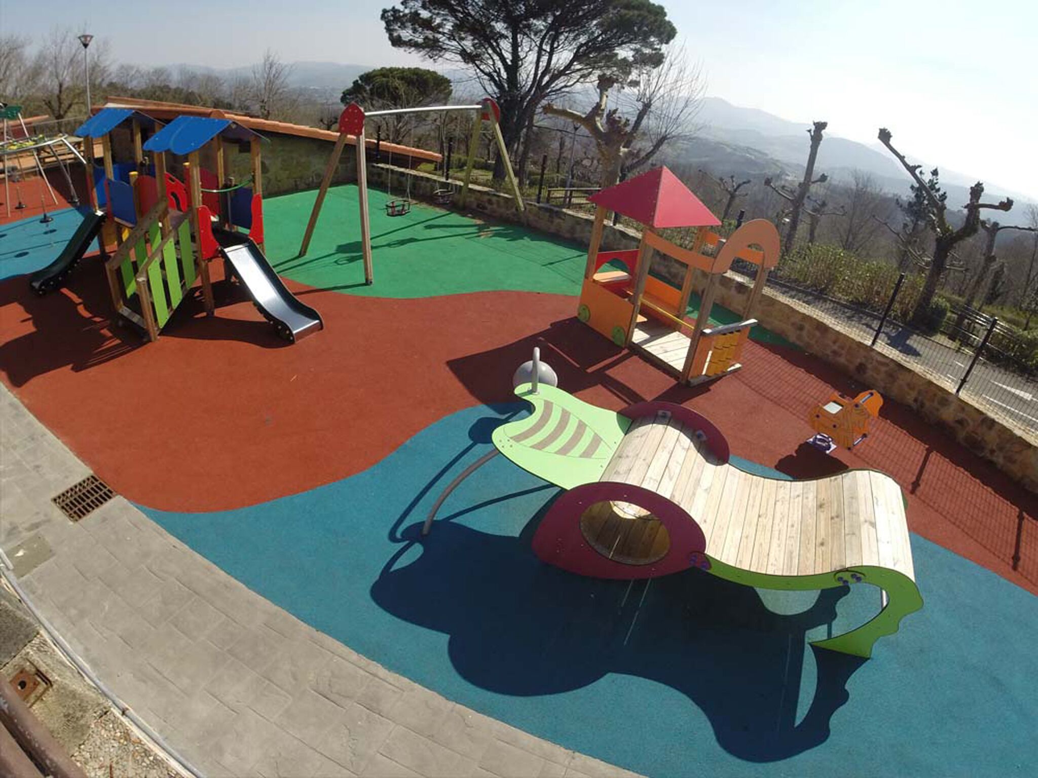 Un parque infantil con un tobogán, estructuras para escalar y una zona de juegos de madera.