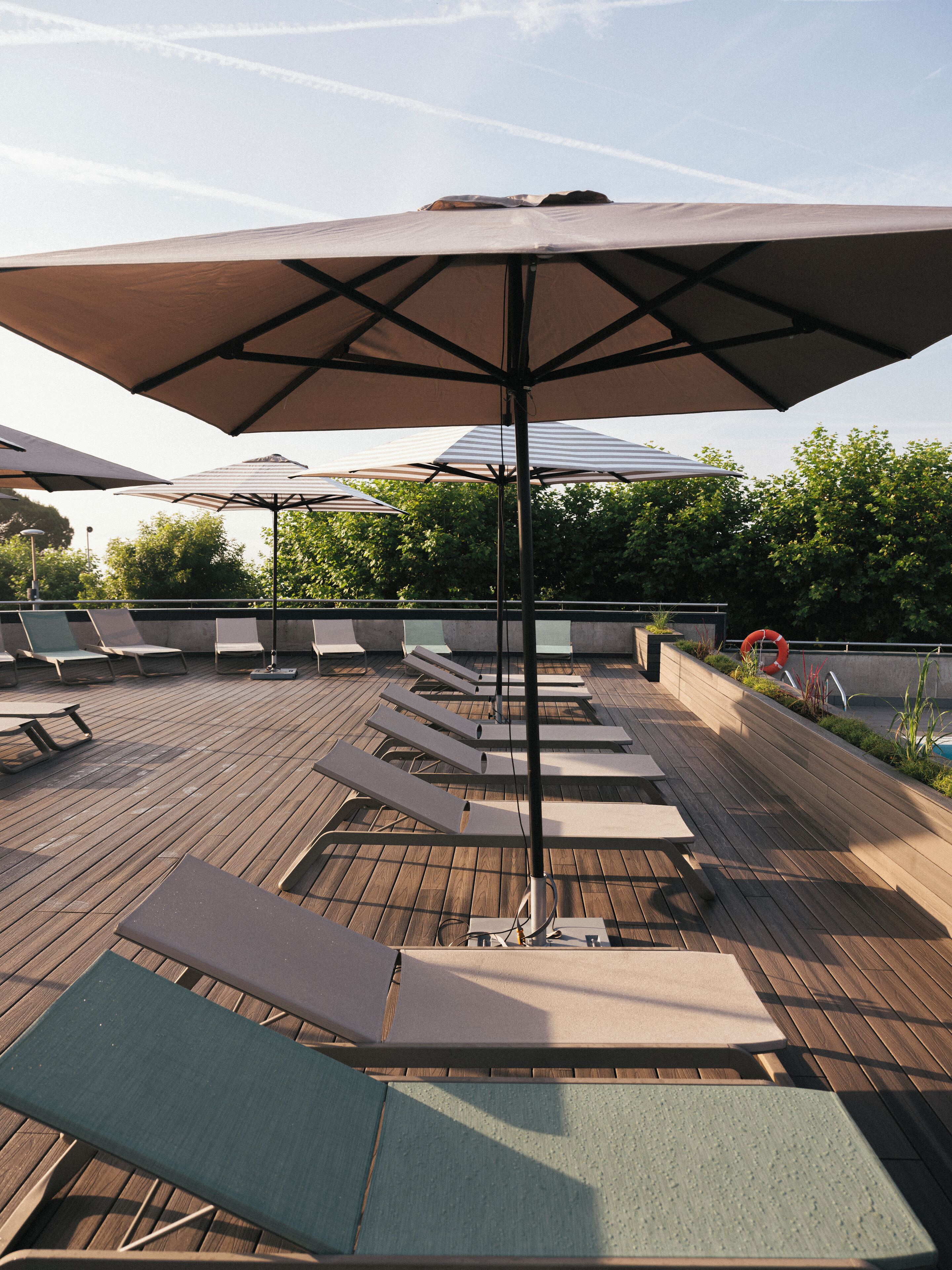 A rooftop terrace with lounge chairs and umbrellas.