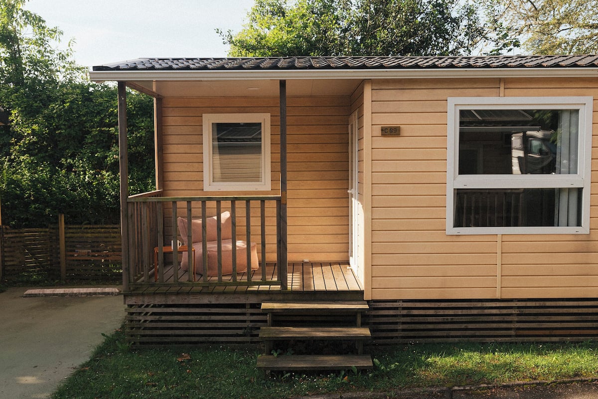 A small, single-story mobile home with a porch and a garage.