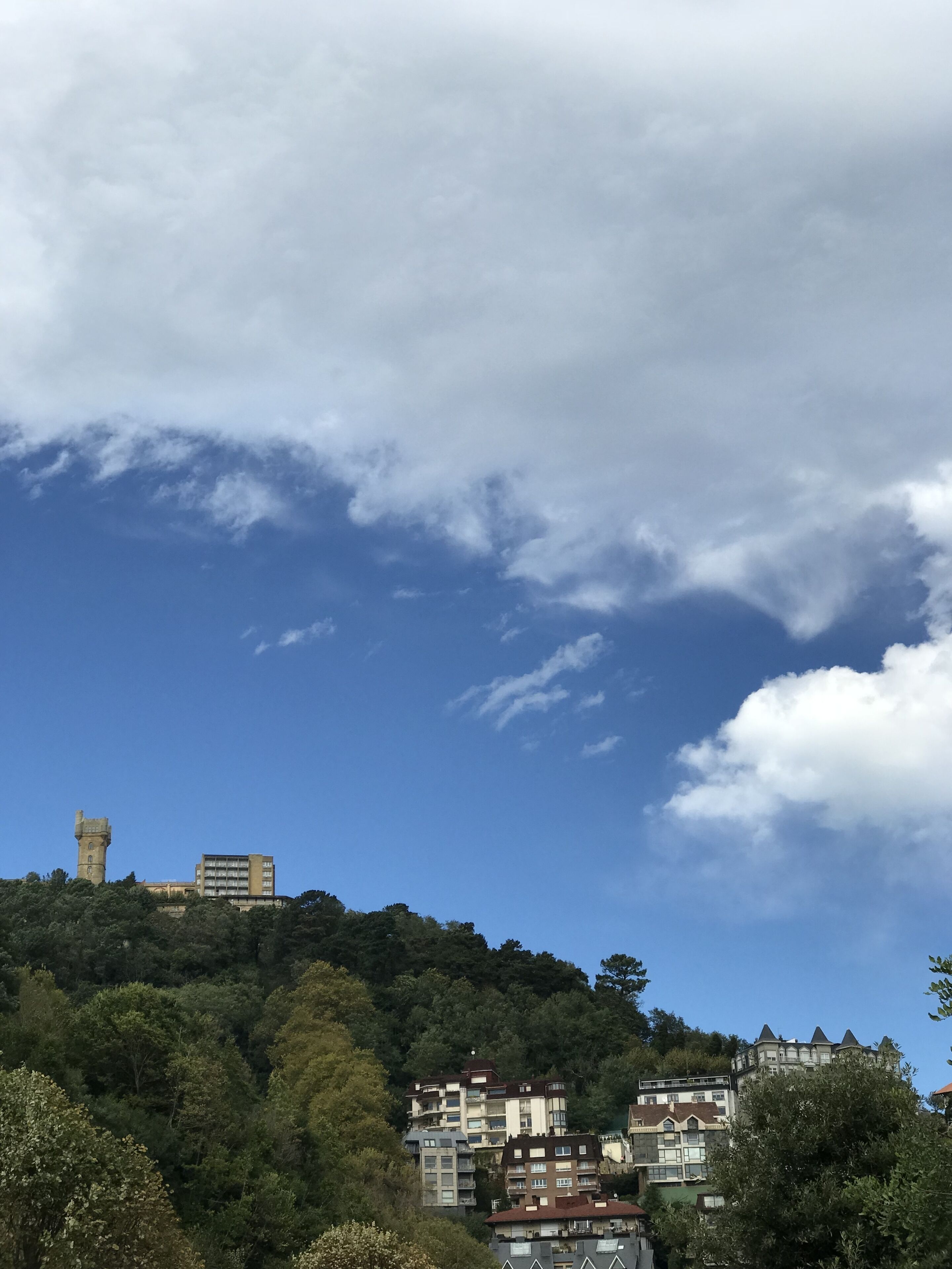 A hilltop view with a tower and residential buildings.
