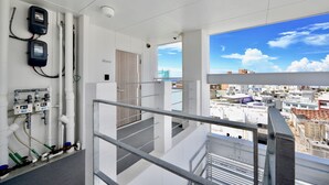 A modern hotel interior with a balcony offering a city view, a staircase, and visible plumbing infrastructure. - Allstay Kotobuki (Naha)
