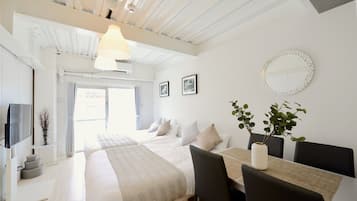 A modern hotel room with a large bed, a dining area, and a TV.