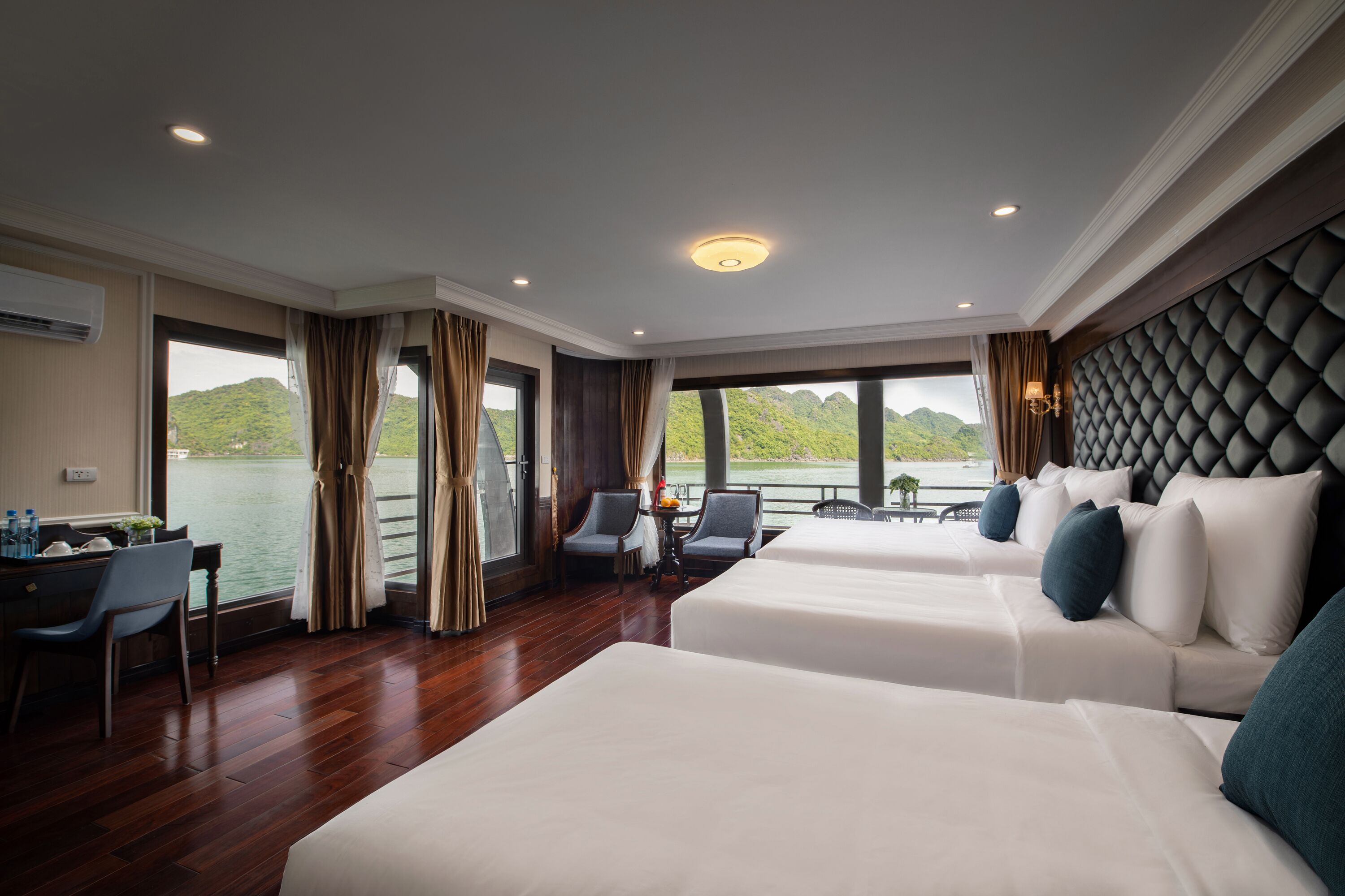 A hotel room with two beds, a desk, chairs, and a view of a lake.