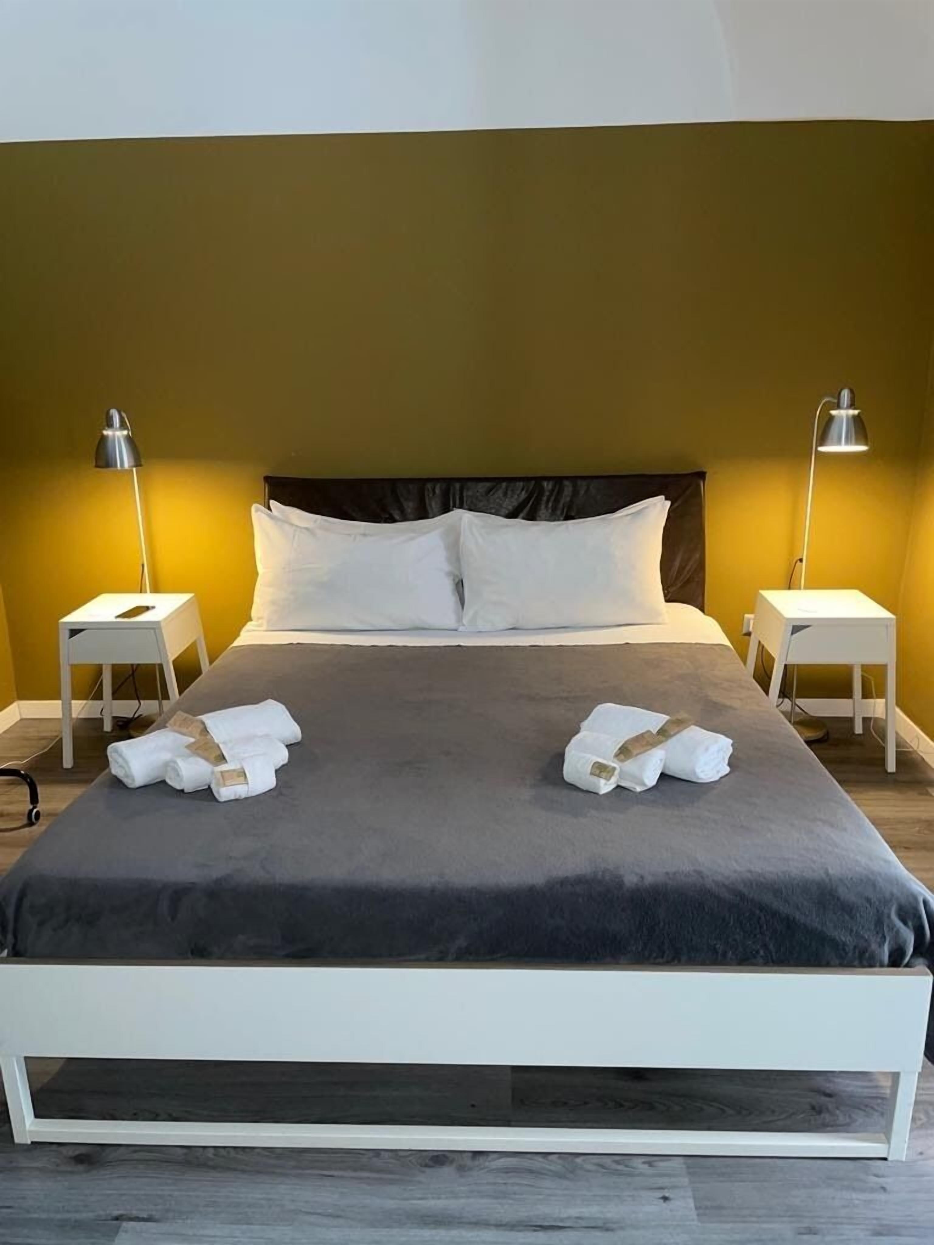Un lit bien fait, avec du linge de lit blanc et deux serviettes pliées au pied du lit.