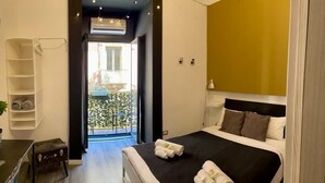 Habitación de hotel moderna con una cama grande, un escritorio pequeño, una silla y un balcón con vistas.