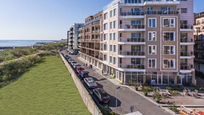 Un hotel de varios pisos con balcones, estacionamiento y vista a la playa.