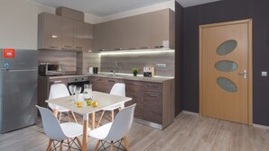 Cocina moderna con comedor, que incluye un refrigerador, microondas, lavabo y una puerta de madera con paneles de vidrio.