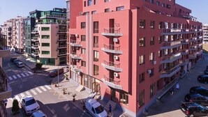 A multi-story residential building with balconies, a parking area, and a clear sky. - Sea Breeze Pomorie (Pomorie)