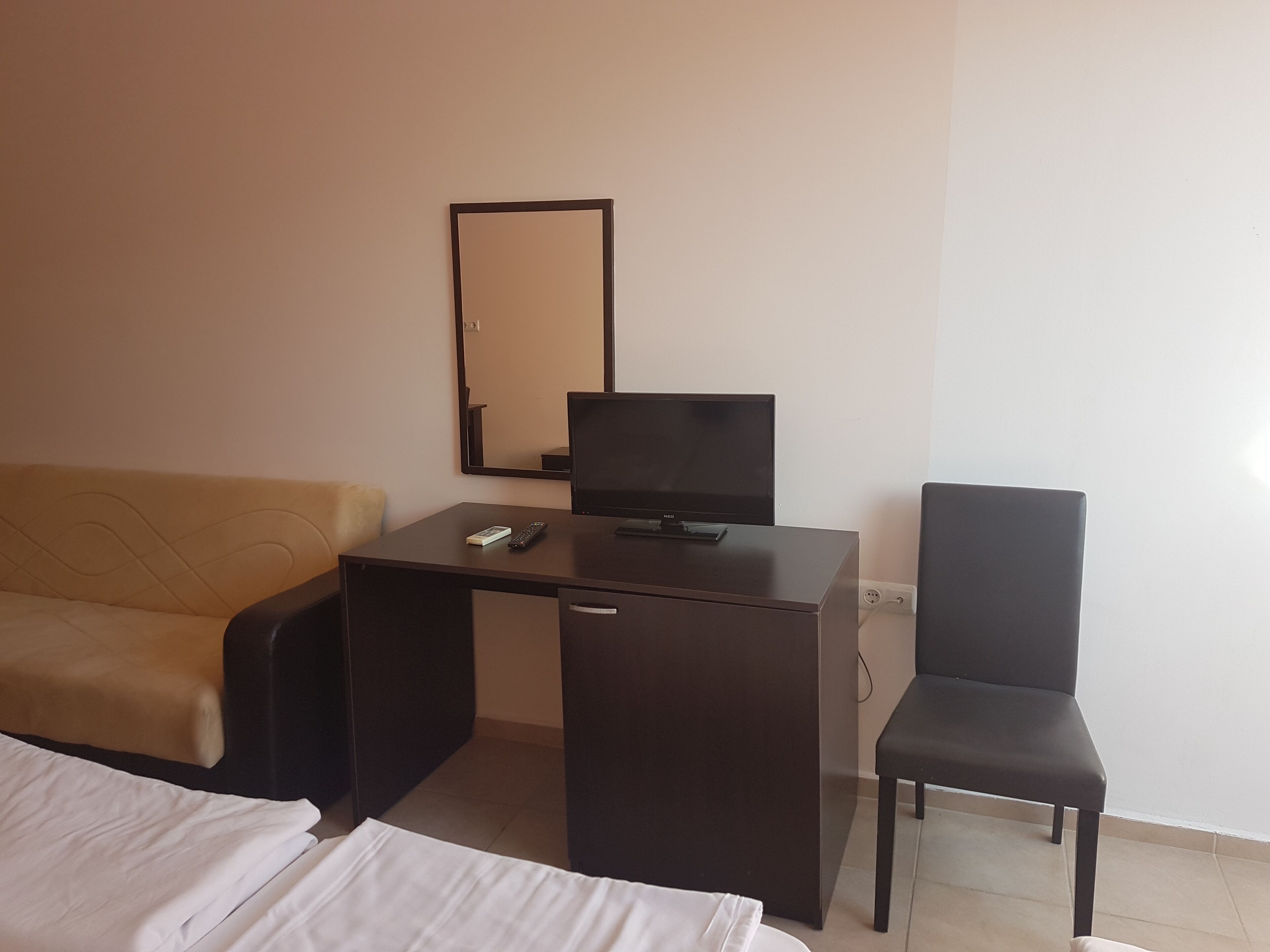 Una habitación de hotel con cama, escritorio con televisor, sillón y sofá.