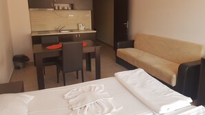 A compact hotel room with a kitchenette, a sofa, and two beds. - Sea Breeze Pomorie (Pomorie)