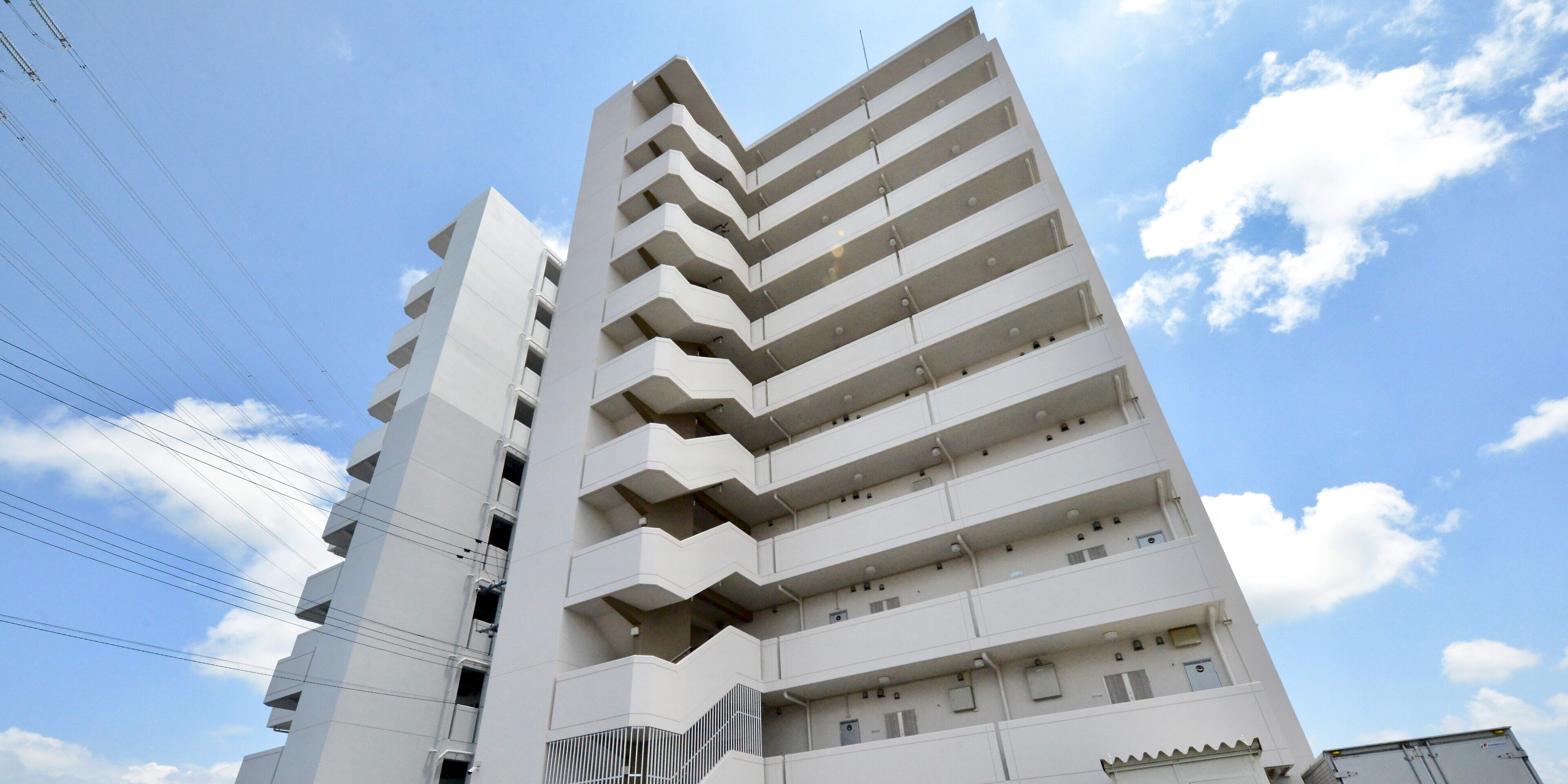 A multi-story building with balconies, a clear sky, and visible power lines.