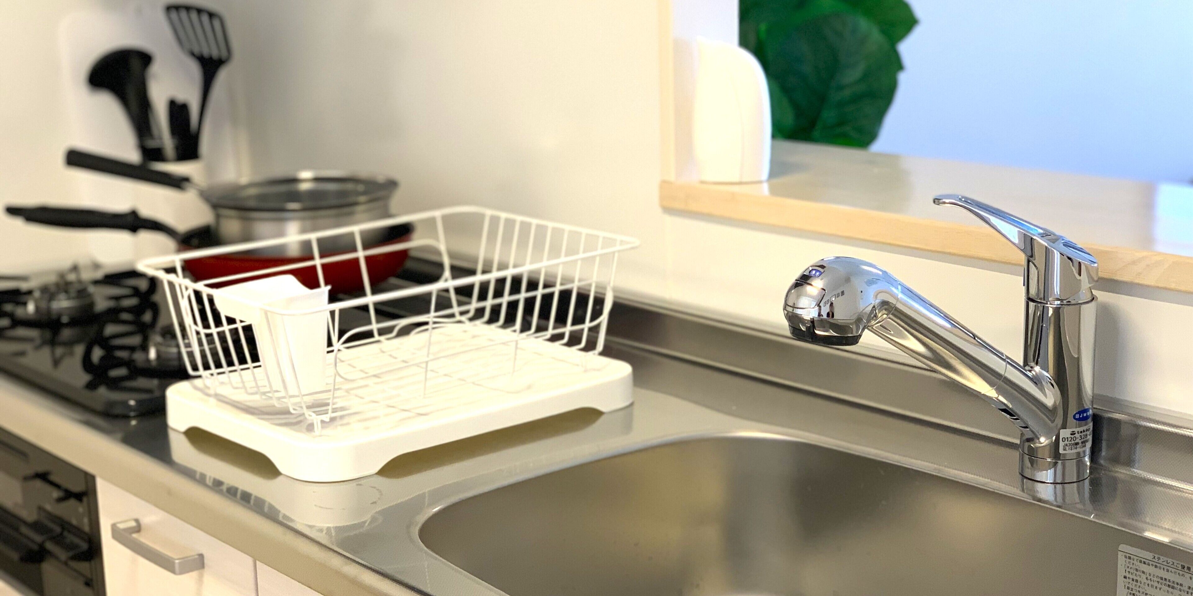 Une cuisine équipée d’un évier en acier inoxydable, d’un égouttoir et d’une cuisinière à gaz.