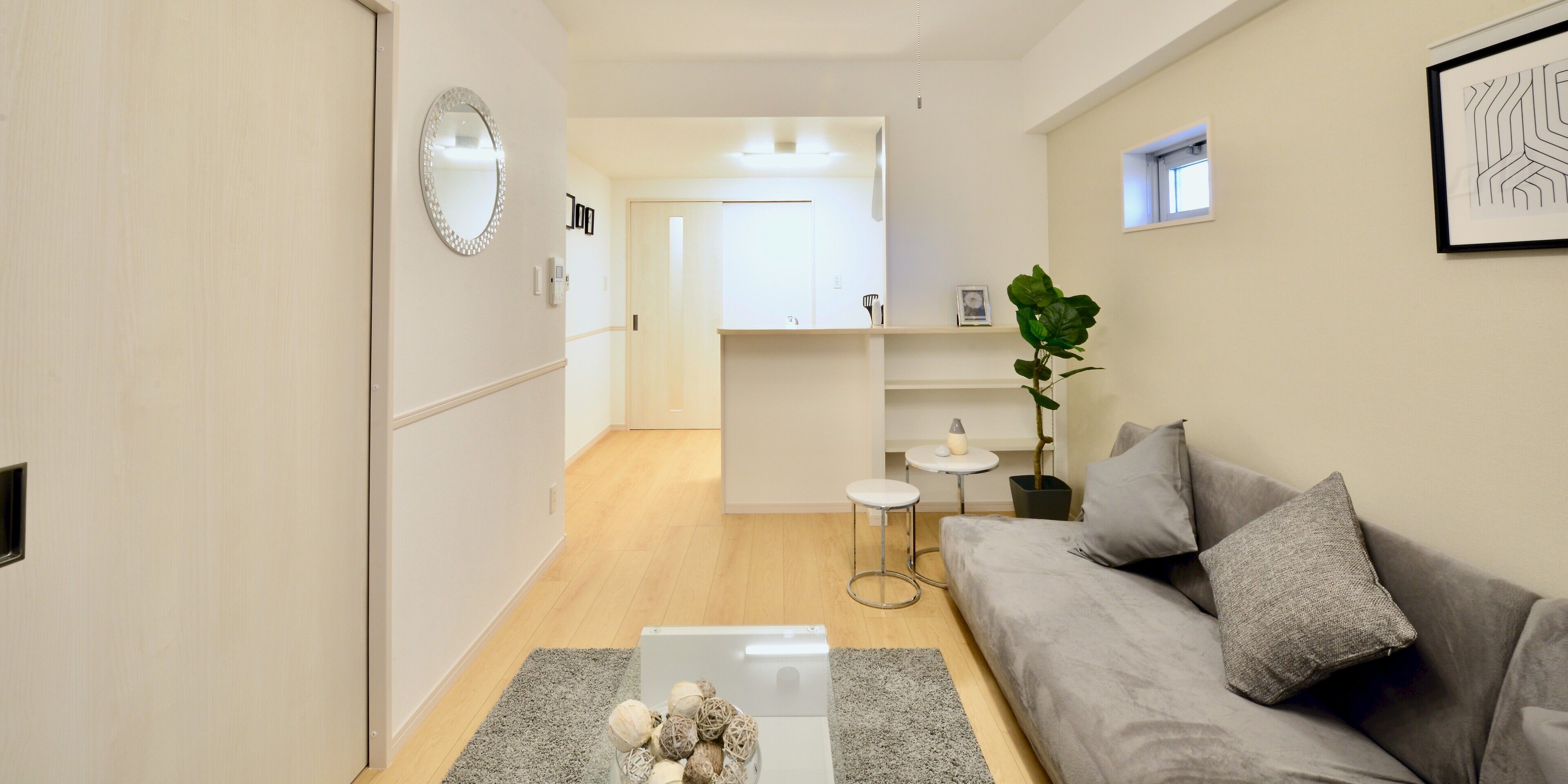 Una sala de estar moderna con un sofá gris, una mesa de centro y una planta.