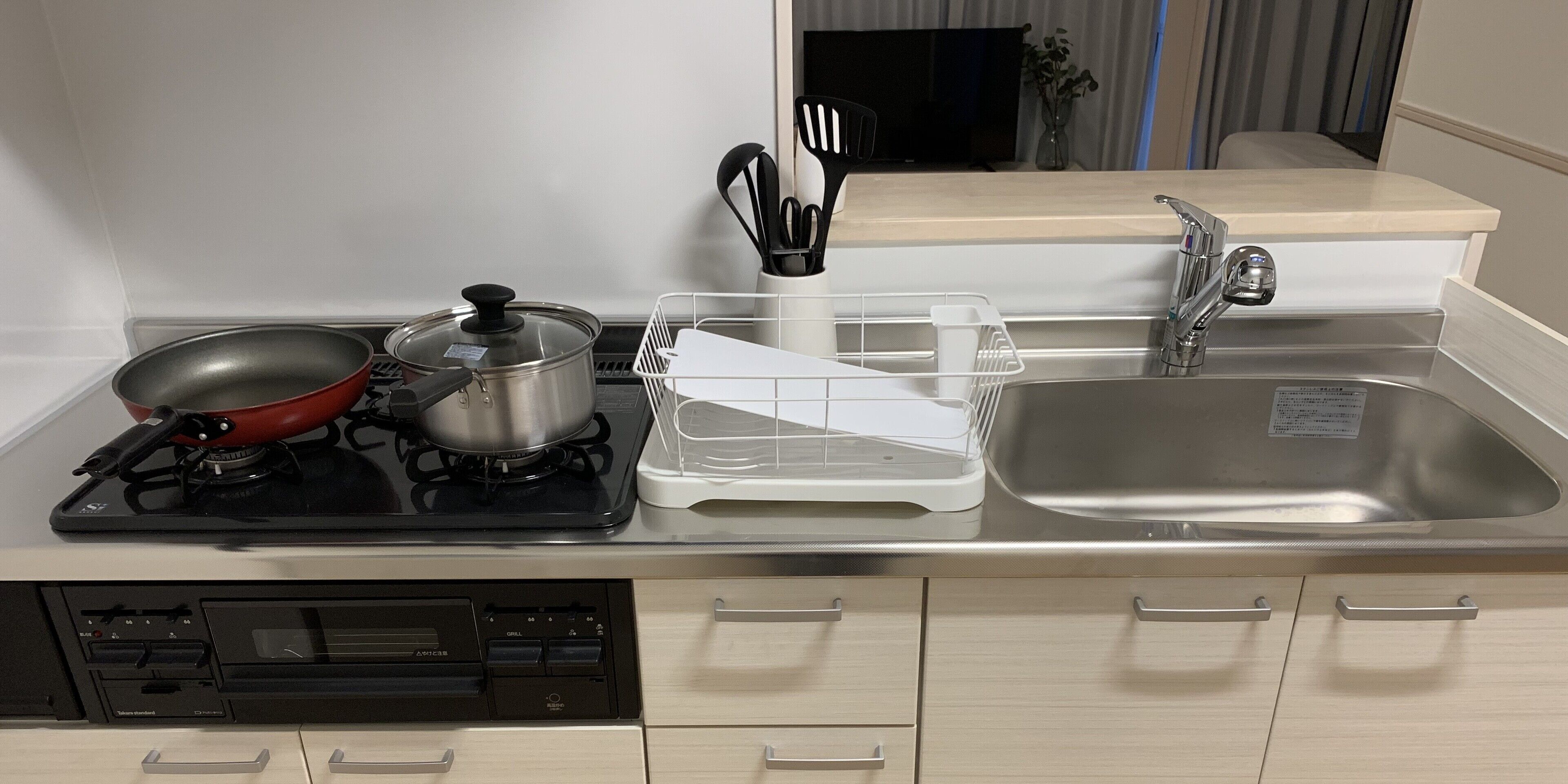 A kitchen with a stove, pots, a sink, and a dishwasher.