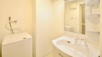A bathroom with a white sink, mirror, and a white washing machine.