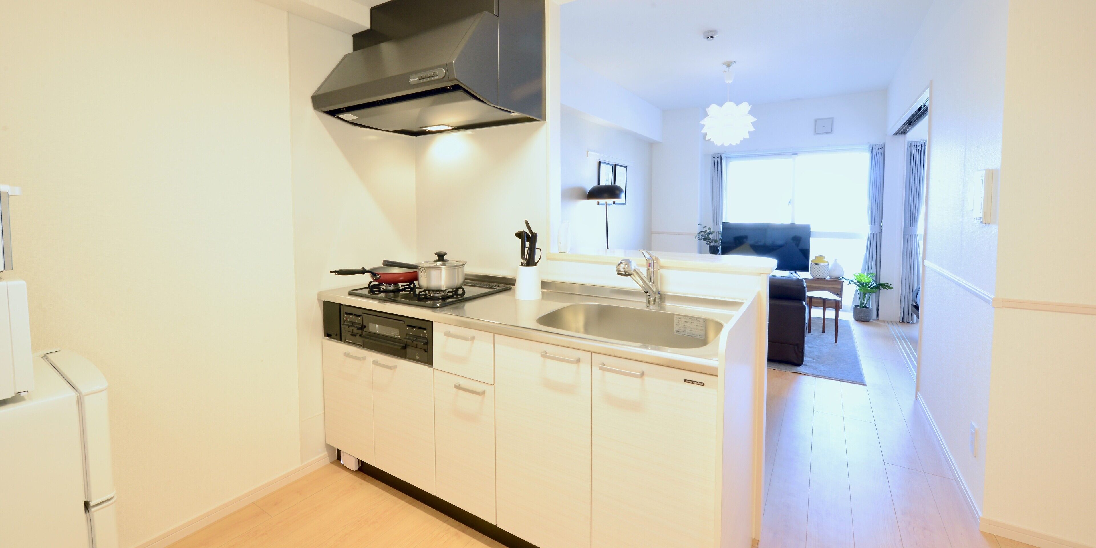 A modern kitchen with a dishwasher, stove, and sink. There is a dining area with a table and chairs visible in the background.